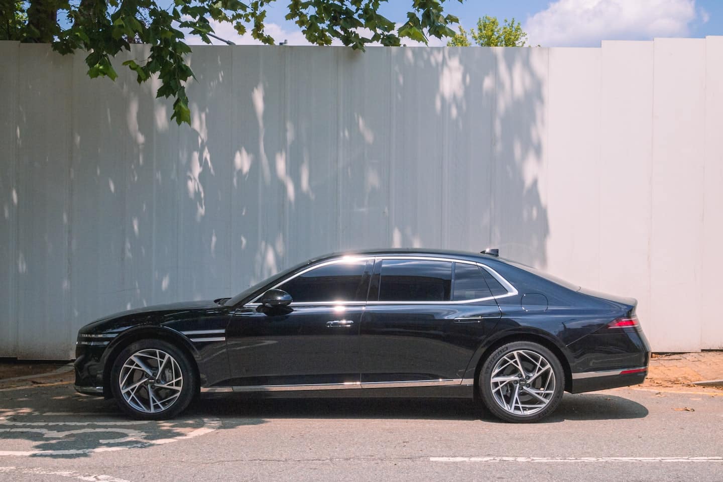 Una berlina di lusso nera parcheggiata all'aperto vicino a un muro di lamiera ondulata.