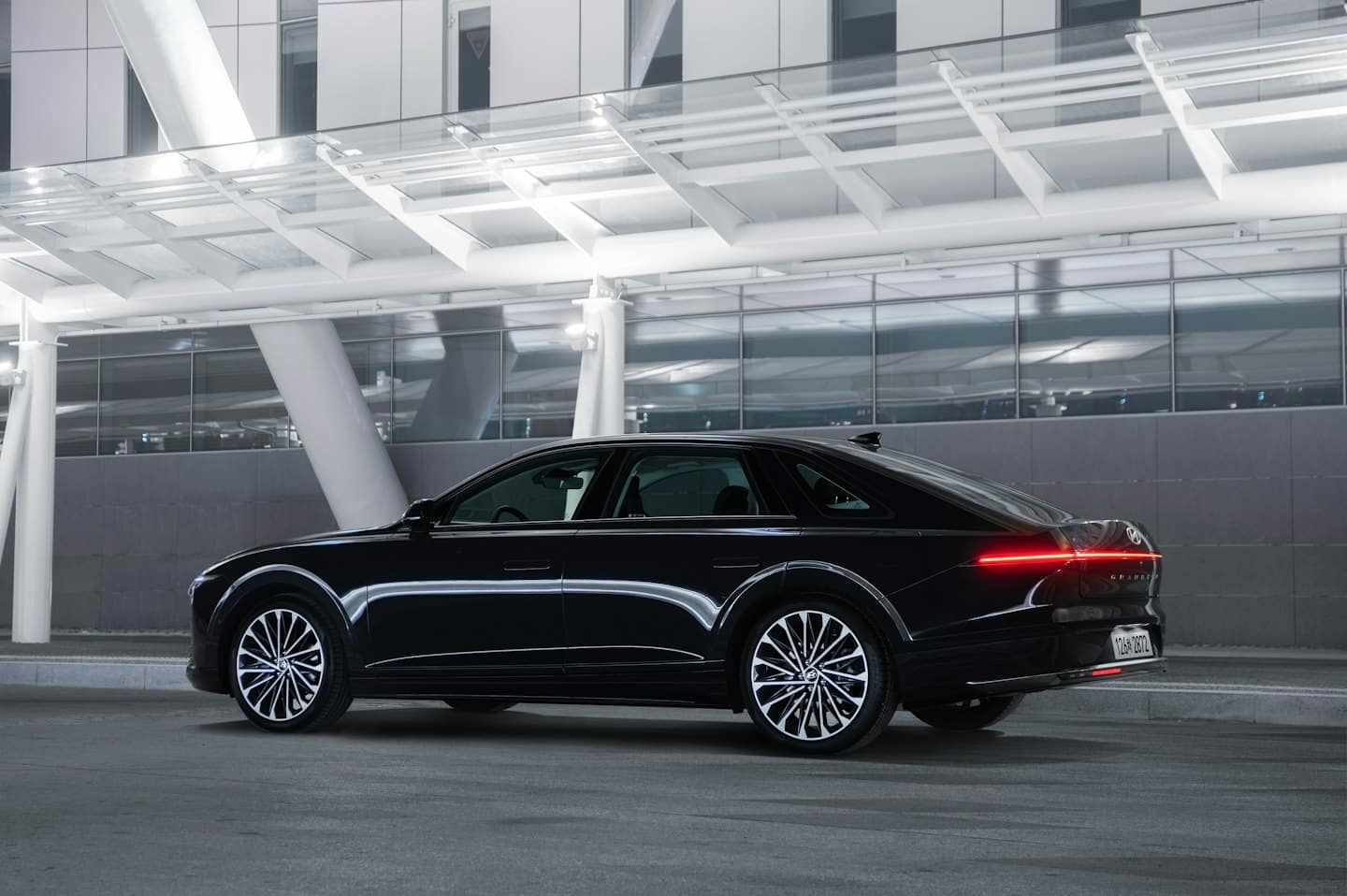 Una berlina di lusso nera parcheggiata accanto a un edificio moderno.